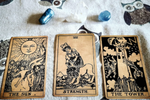 Tarot oplæg der viser The Sun, Strength og The Tower. Bagved er der to blå krystaller og en bjergkrystal.