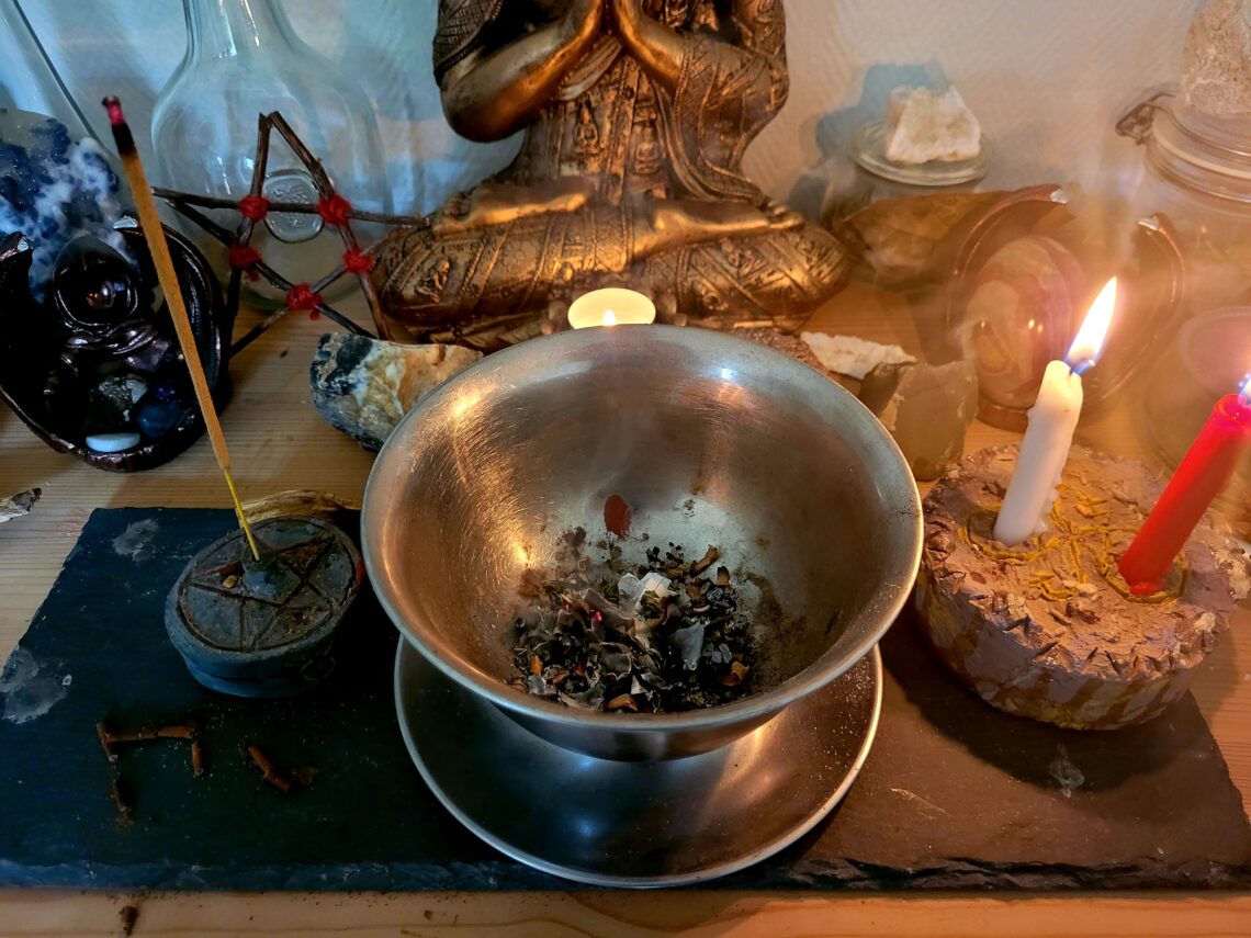 Heksekedel på alter med stearinlys og røgelse