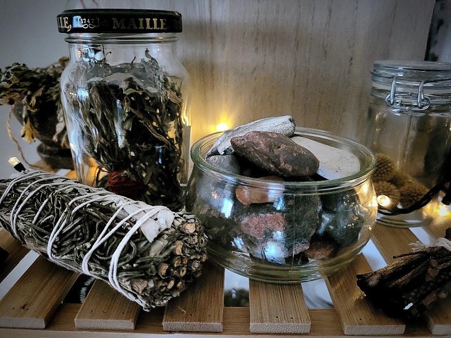 Røgelse og smudge sammen med glas med sten og tørrede urter.