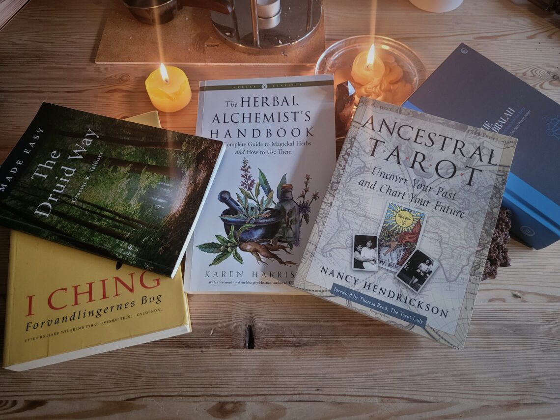 Spirituelle bøger lagt op sammen med krystalller og levende lys